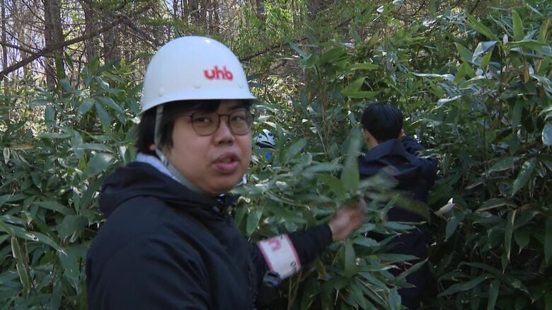 道警の指導のもと笹やぶに入る川瀬雄也記者
