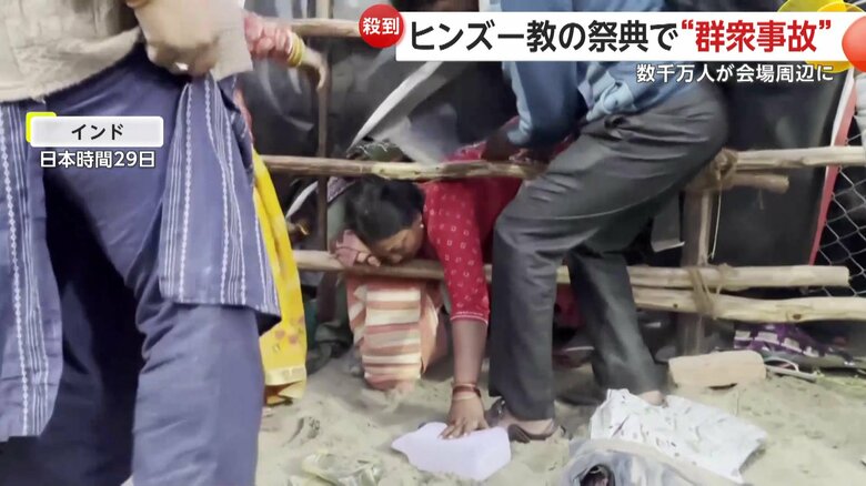 ヒンズー教の宗教行事会場で、柵の間をくぐり抜けようとする人