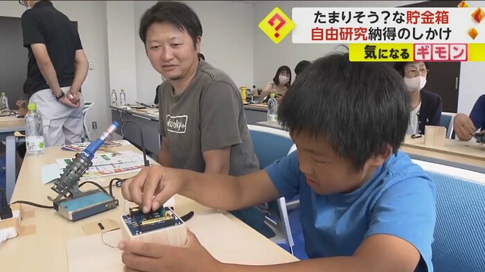 貯金箱にお金を入れる小学生