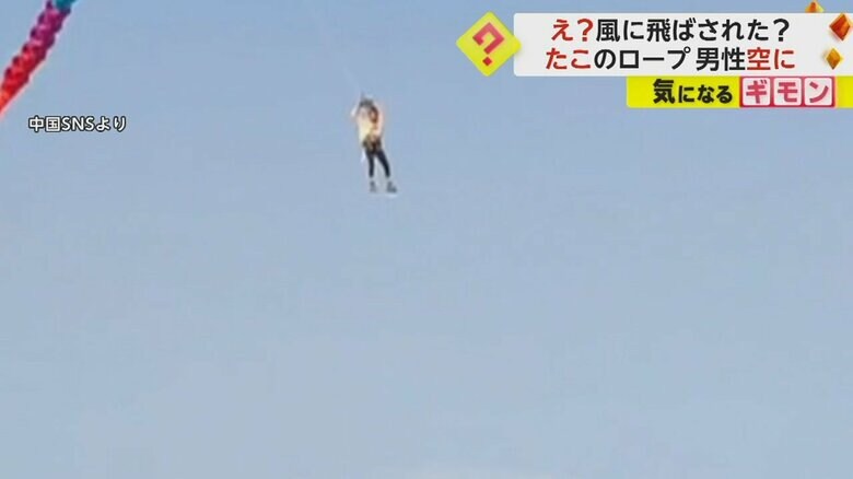 何かに捕まりながら大空を舞う男性