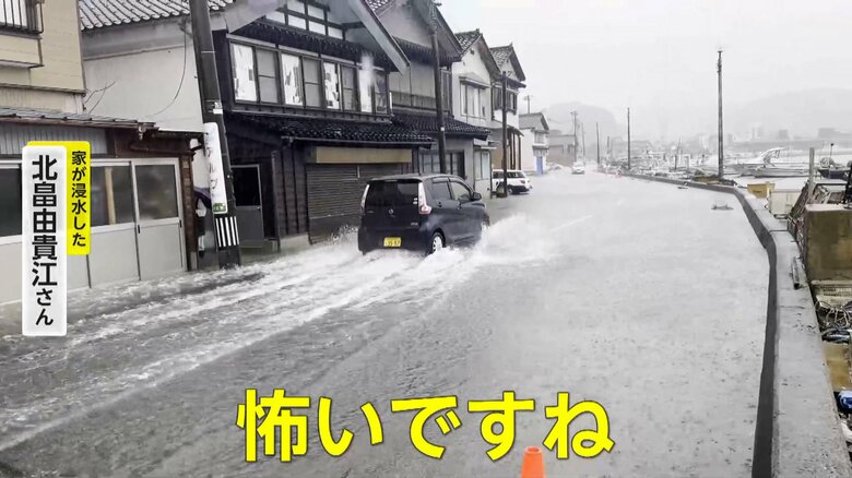 タイヤの半分ほどの高さまで冠水する道路を水しぶきを上げて走る車