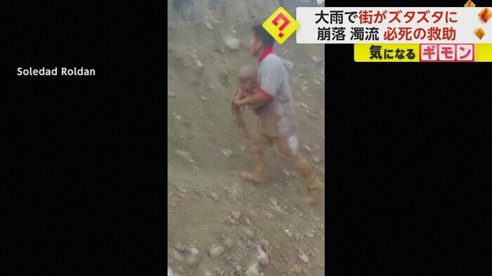 泥まみれの子供を抱きかかえる男性