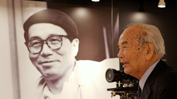 市川崑監督の写真の前で ⼭⼝益夫さん(右)(2024年 市川崑記念室にて)