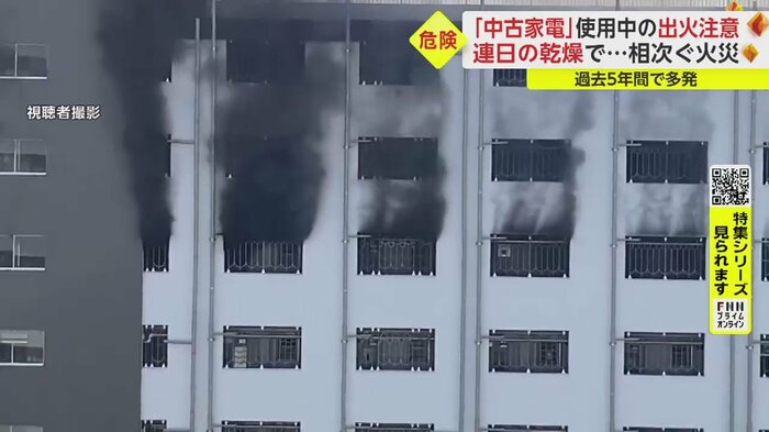火災で内部に充満した黒い煙が共用廊下の窓から噴き出す