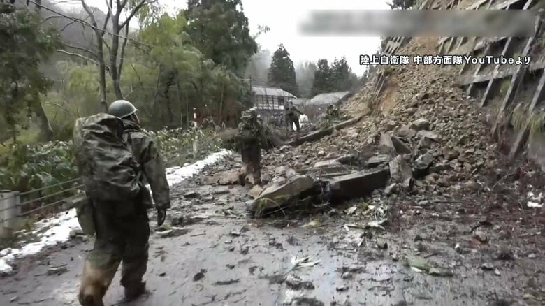 崖崩れの横を進む自衛隊員