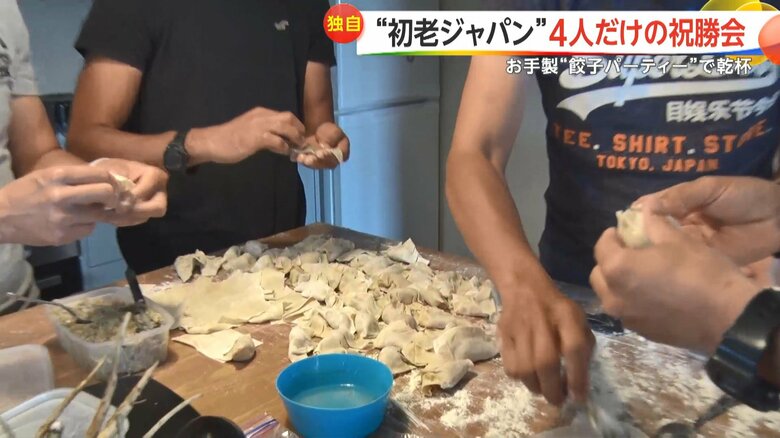 祝勝会の料理を準備する4人。ギョーザを手際よく包む。