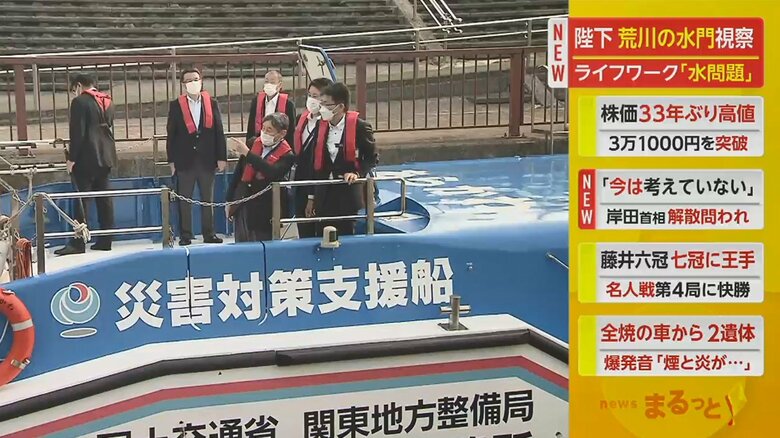 赤いライフジャケットを着用し、船のデッキに立たれる陛下