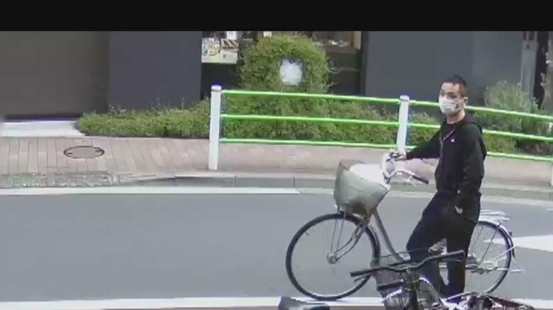 クリーニング店に現れた男。ポケットに手を突っ込みながら、自転車を押している(27日 東京・大田区)