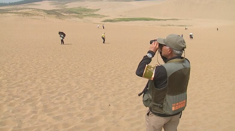 レンジャーが双眼鏡で観光客を見守る　炎天下の砂丘では遠方の異変も見逃せない