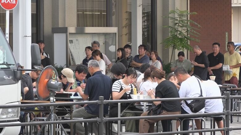 ラーメンをすする客の後方には長い行列が