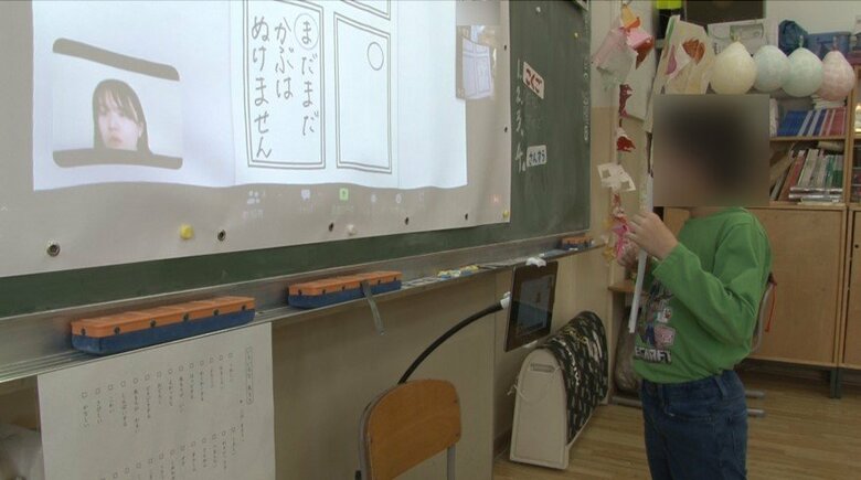 かるた作りの授業でカメラの前に立って作品を見せる小学生（2023年1月）