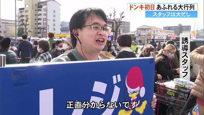 レジ待ち行列の最後尾を案内するスタッフ