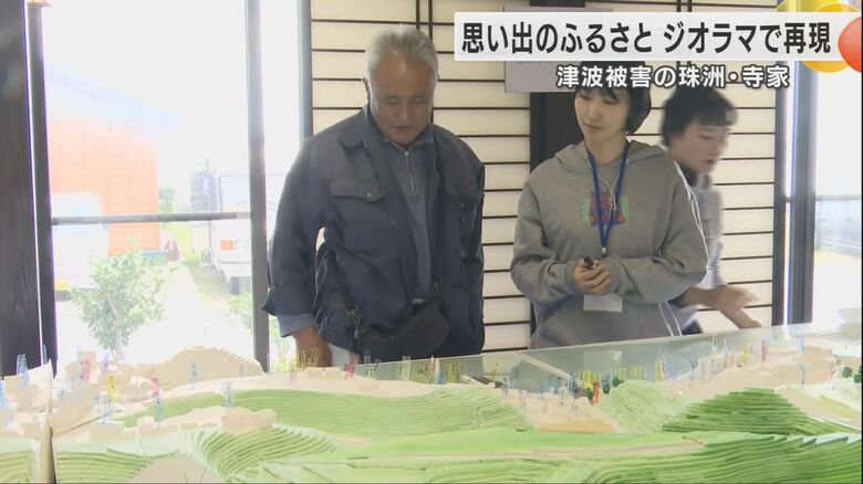 ジオラマの自分の家を見つめる男性