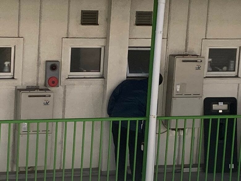 金容疑者の部屋の前で話しかけているとみられる捜査員（視聴者撮影）