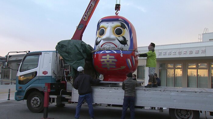 トラックに積まれる巨大ダルマ