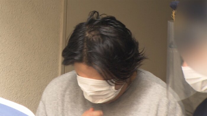 河合容疑者は、報道カメラを目にすると、サッとマスクを広げて、顔を隠した(7日 築地署)
