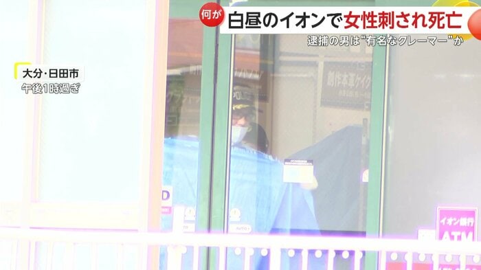 店の扉をブルーシートで覆う警察官