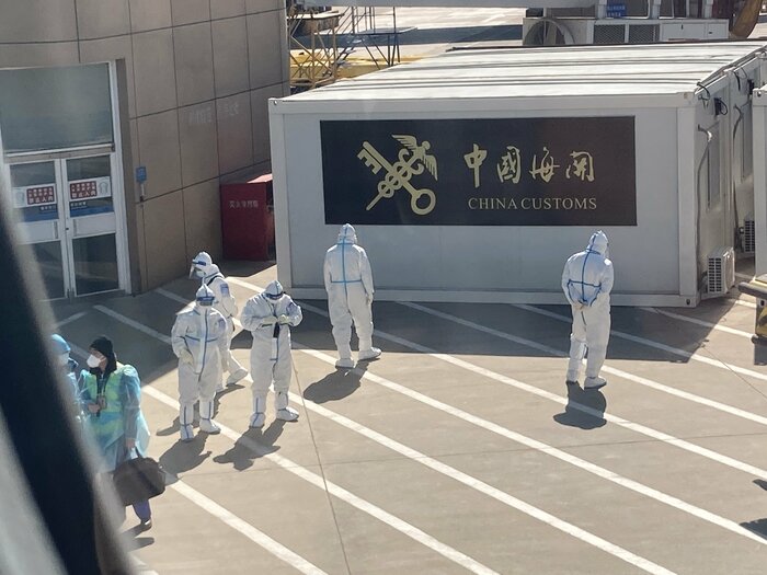 機体の下で待機する全身防護服の係官