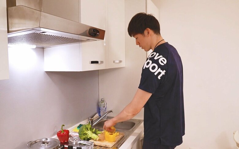 自宅のキッチンで料理をする石川
