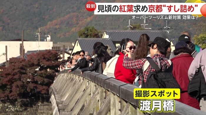 美しい紅葉の嵐山をバックに写真を撮ろうと、観光客がずらりと並んでいる