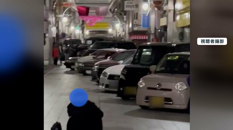 並んだ車の前で座り込む人 撮影しているのか?