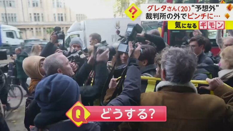 ロンドンで裁判後のグレタさんにかけ寄る報道陣と、横断幕でグレタさんを守るデモ参加者