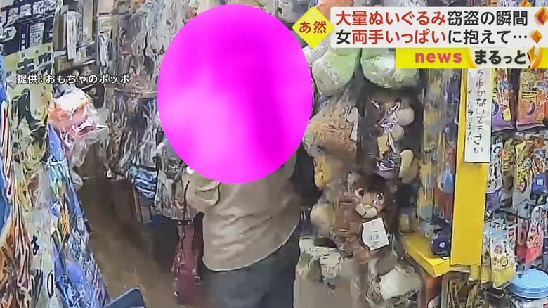 白っぽい上着にピンク色のバッグを持ち、商品を見ている女