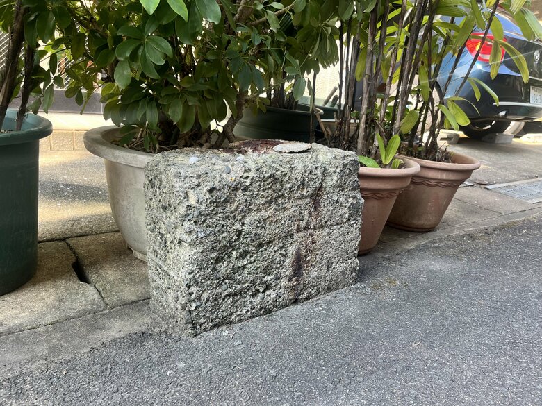 歩道の端に幽霊の恩返し「幽霊井戸の跡」とされるコンクリートの塊が残されている