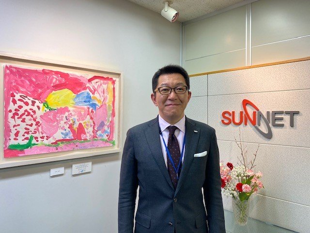 サンネットの市川聡社長。障がいのある人たちの描く絵をオフィスに飾っている