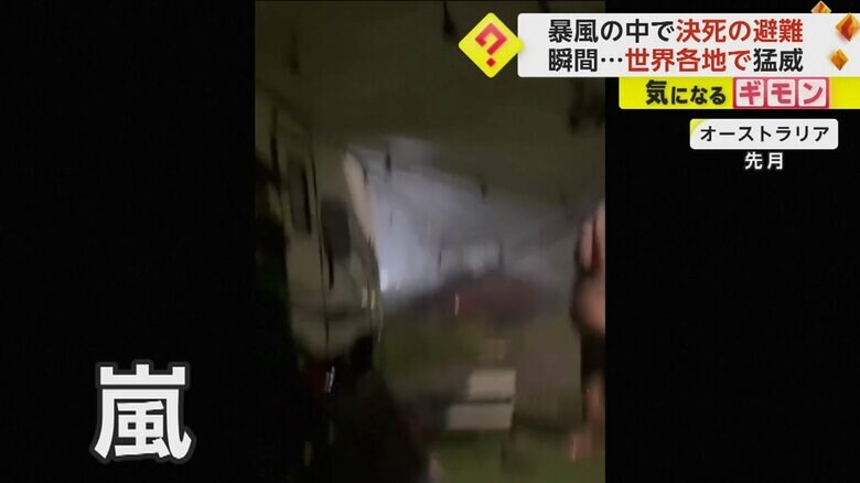 上半身裸の男性が、ひさしが飛ばないよう押さえている様子