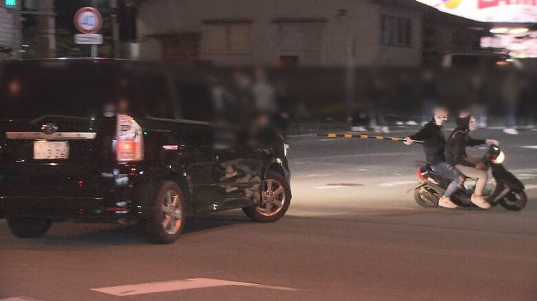 黒い車が原付バイクをあおる