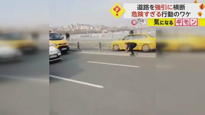 中央分離帯で腰をかがめる女性