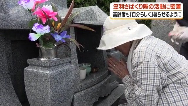 墓前で静かに手を合わせる女性