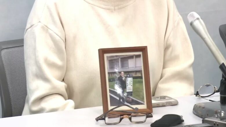 俊夫さんの写真とともに取材に応じる雅子さん