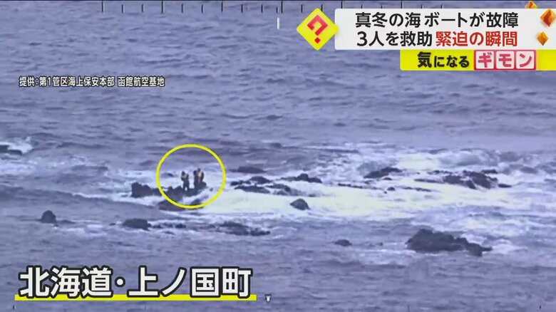波しぶきがあがる海で岩場に立っている3人