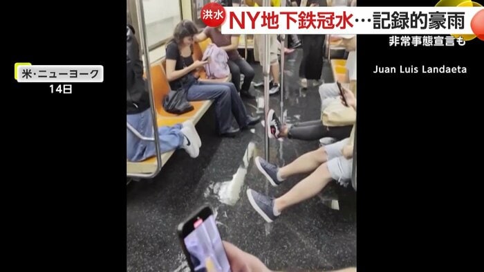 水浸しの車内で水を避けようとしている乗客たち