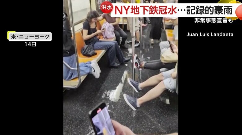 水浸しの車内で水を避けようとしている乗客たち