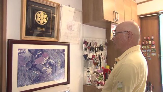 かつての自宅の写真を見つめる松永さん