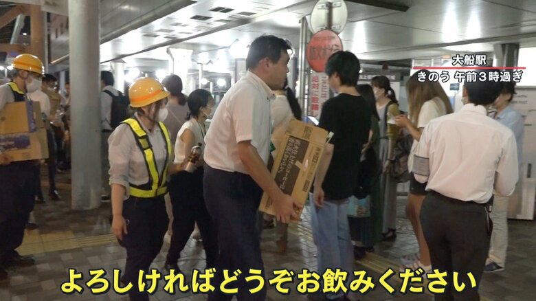 タクシーの待機列に飲み物を配るJR職員