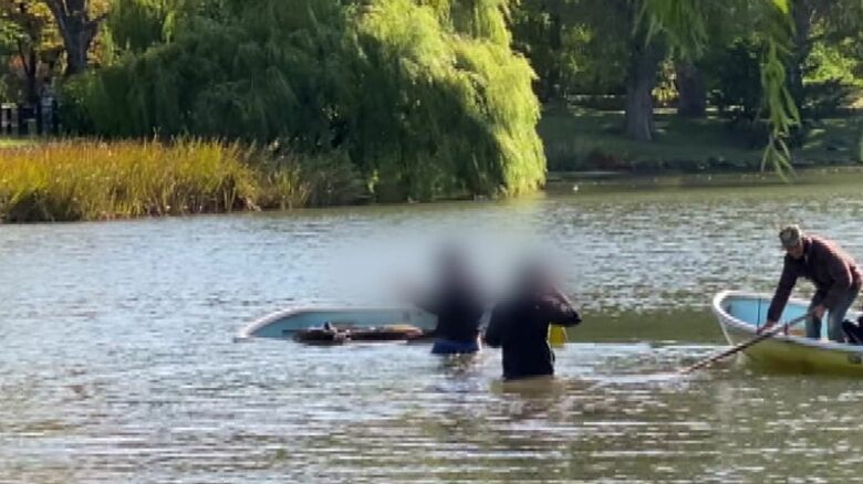 浸水して傾いたボートのそばで困惑した様子の男性2人（提供：視聴者）