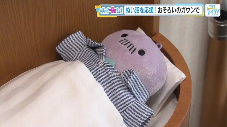 小さなベッドで休む、ぬいぐるみの「ハンザキ」さん