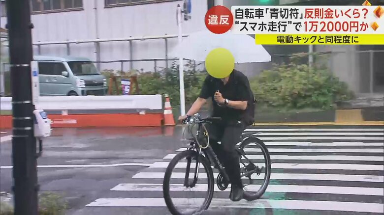 傘をさしながら自転車に乗る人