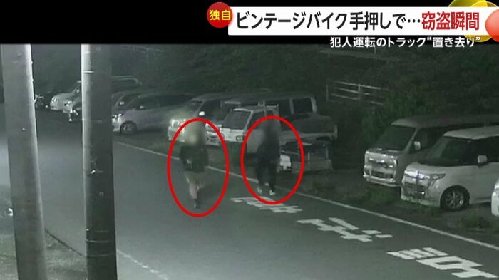 中古車販売店の駐車場に車を止め、店に向かう2人組(5月11日、千葉・四街道市)