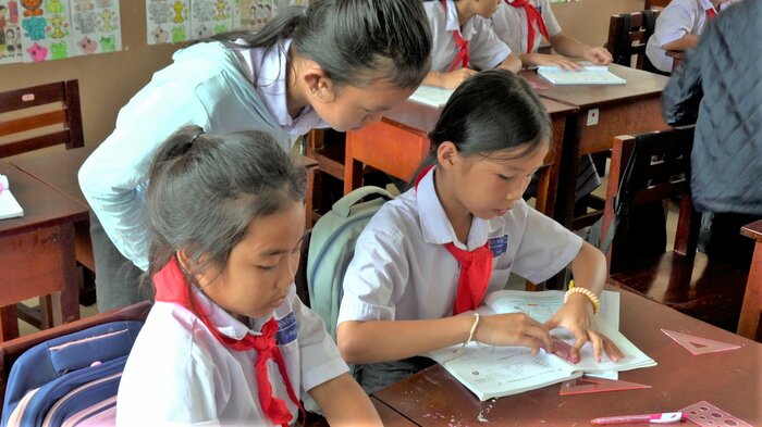 ドンカムサン教員養成校・付属小学校でJICAが開発した算数の教科書を使って学ぶ児童