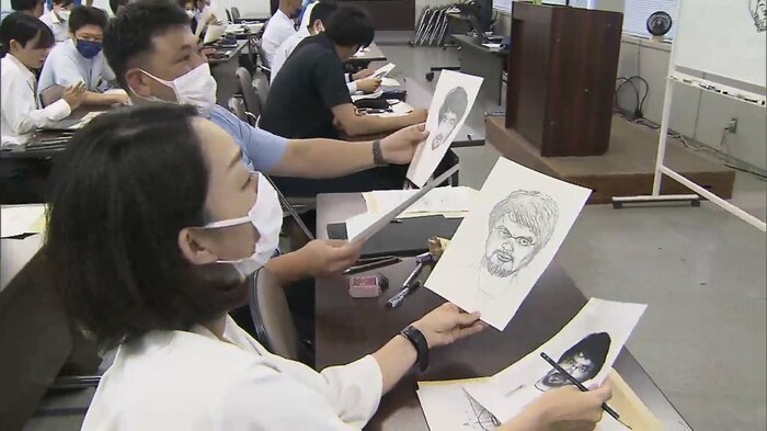 似顔絵と写真を見比べる似顔絵捜査員