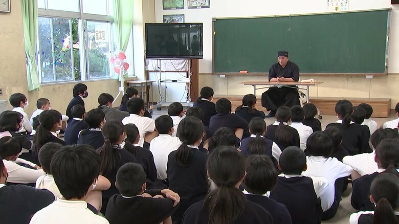 和菓子職人・片岡圭助さんの話を聞く児童たち