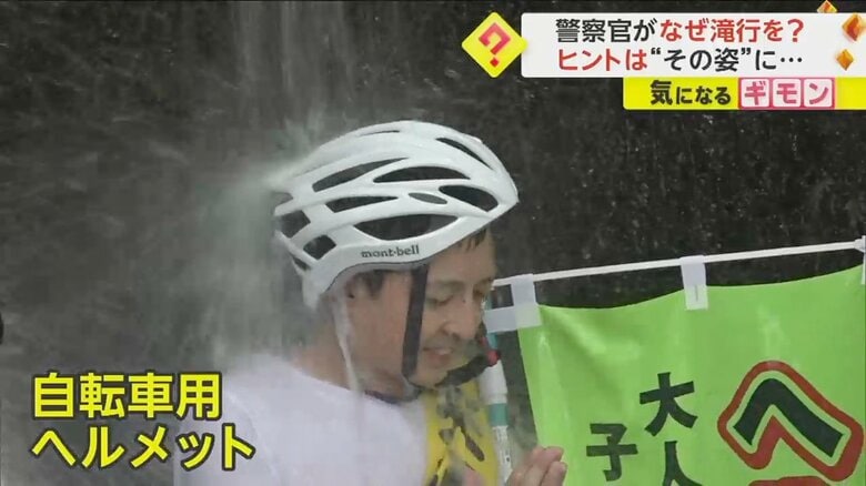 自転車用ヘルメットをかぶりながら滝に打たれる警察官