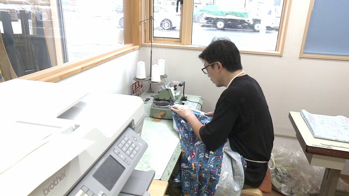 外からも見える作業場で生地を縫い上げていく高さん