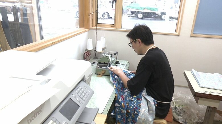 外からも見える作業場で生地を縫い上げていく高さん