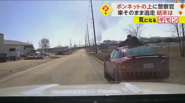車の屋根の上に警察官がしがみついている
